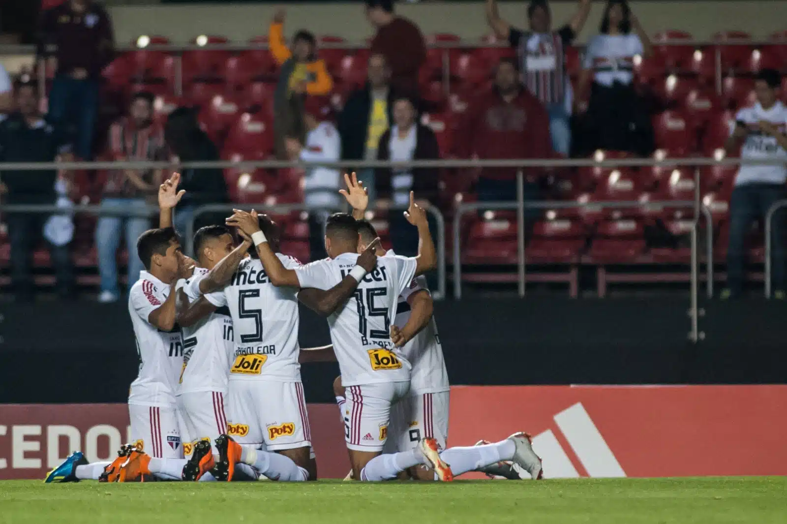 Jogadores do São Paulo se abraçam e comemoram com os braços voltados para cima